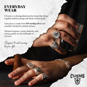 The image is a close-up of a person's hands wearing various pieces of jewelry, including multiple rings and a bracelet.