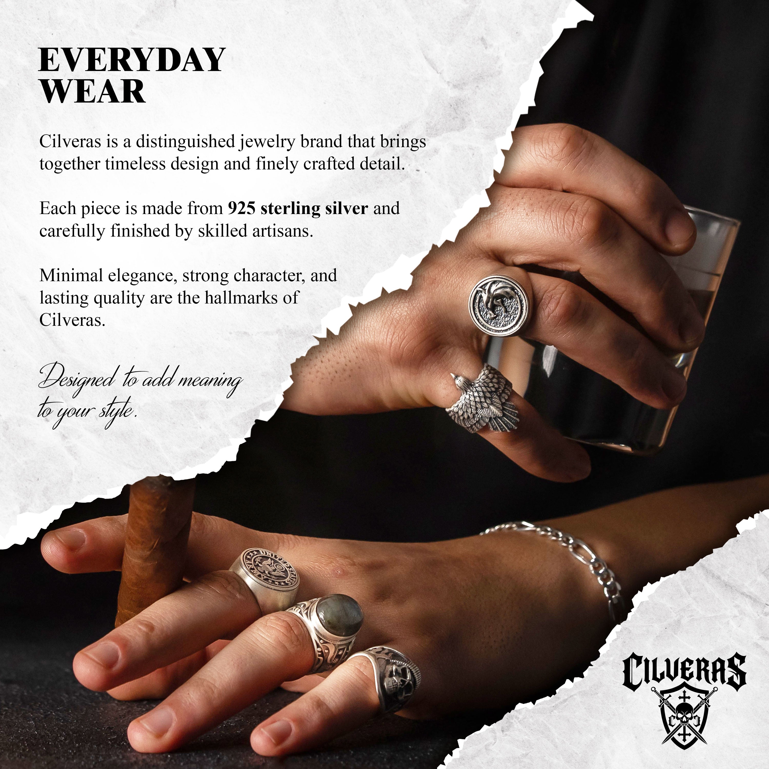 The image is a close-up of a person's hands wearing various pieces of jewelry, including multiple rings and a bracelet.